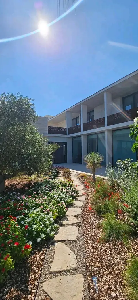 Flagstone stepping stones between beds of red and white flowers, leading toward a modern building