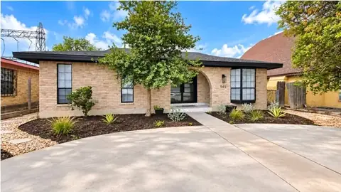 The same home after, with curved beds of dark mulch, young plants and a light gravel border