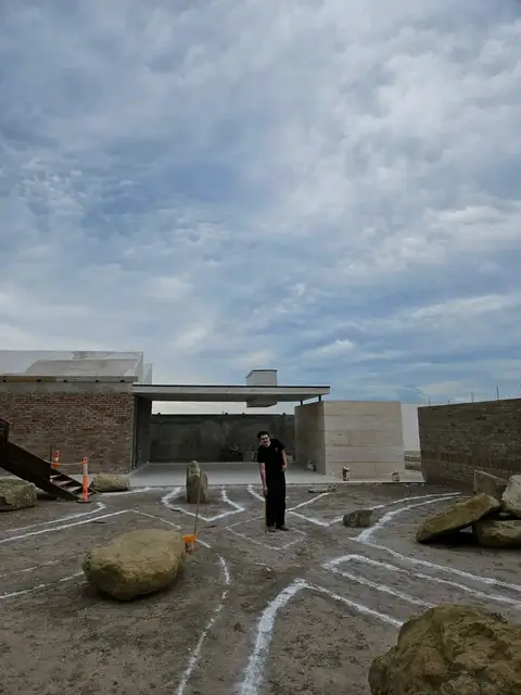 White chalk lines marking out a layout on bare ground, with boulders and a person standing in the space