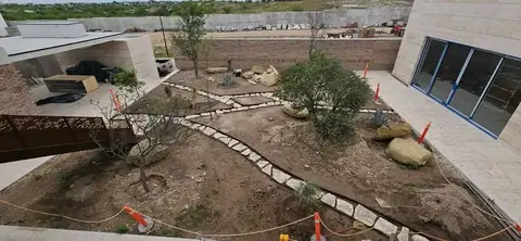 Stone-edged paths and boulders set into bare soil, with orange safety cones